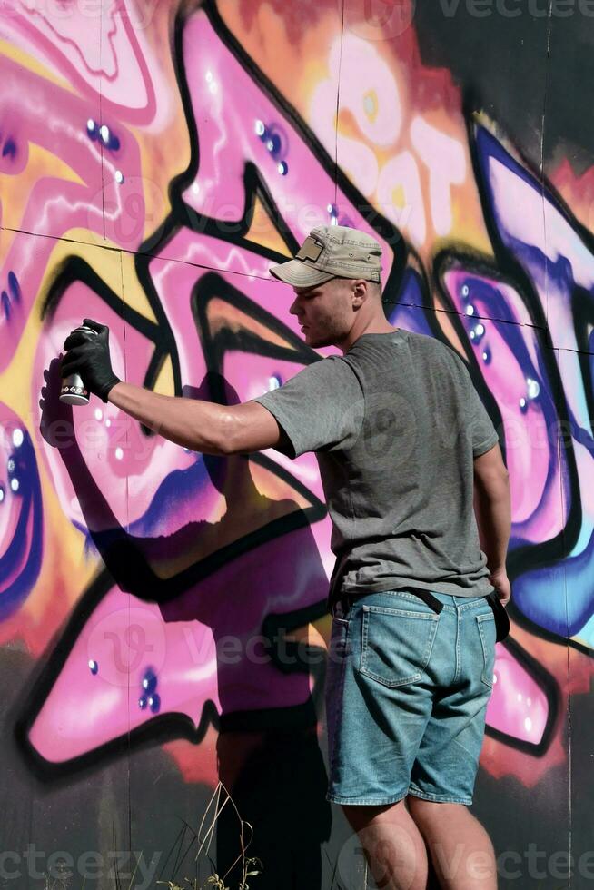 jong Kaukasisch mannetje graffiti artiest tekening groot straat kunst schilderij in blauw en roze tonen foto