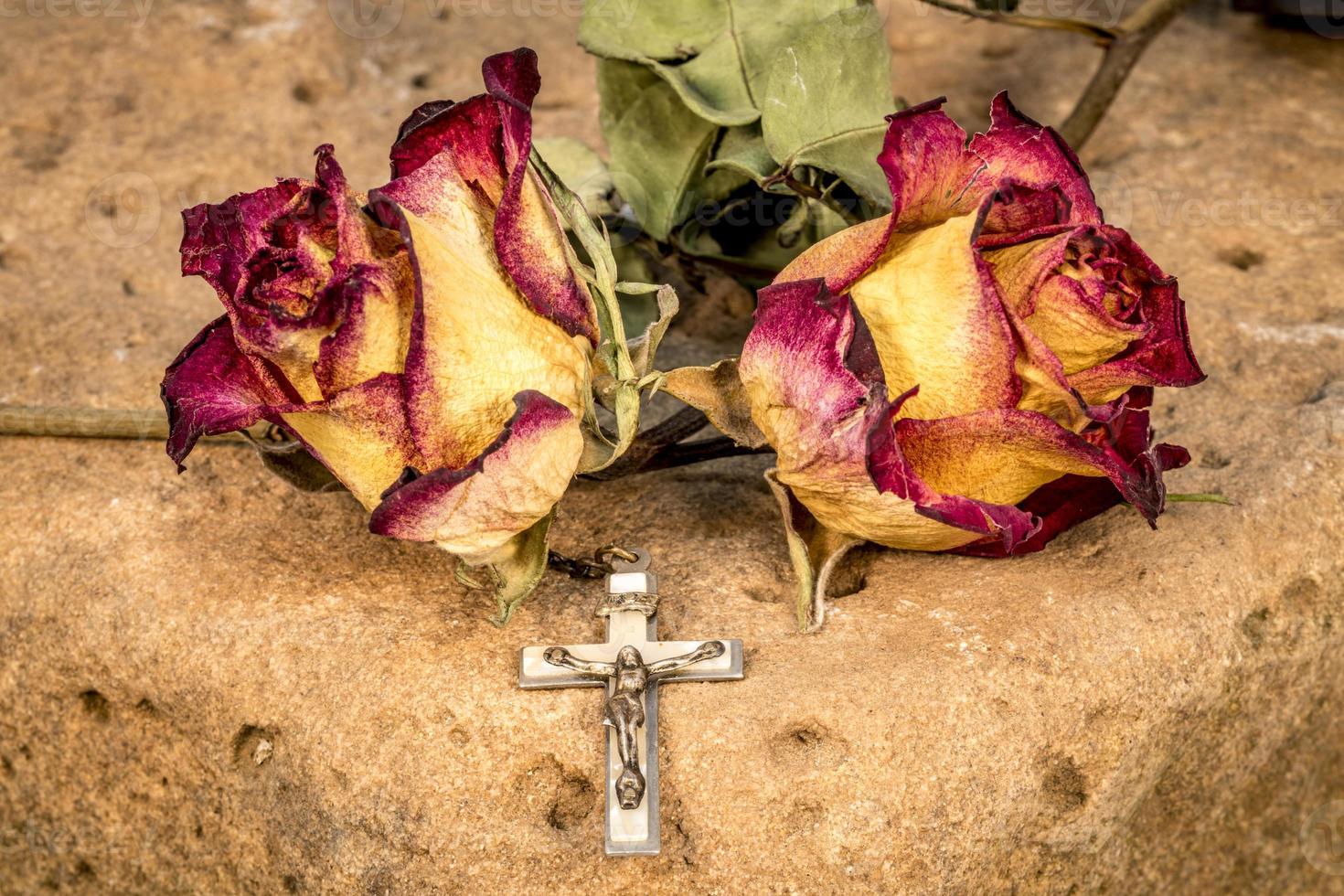 christelijk kruis op rozenkrans en een droge gele rode rozen foto