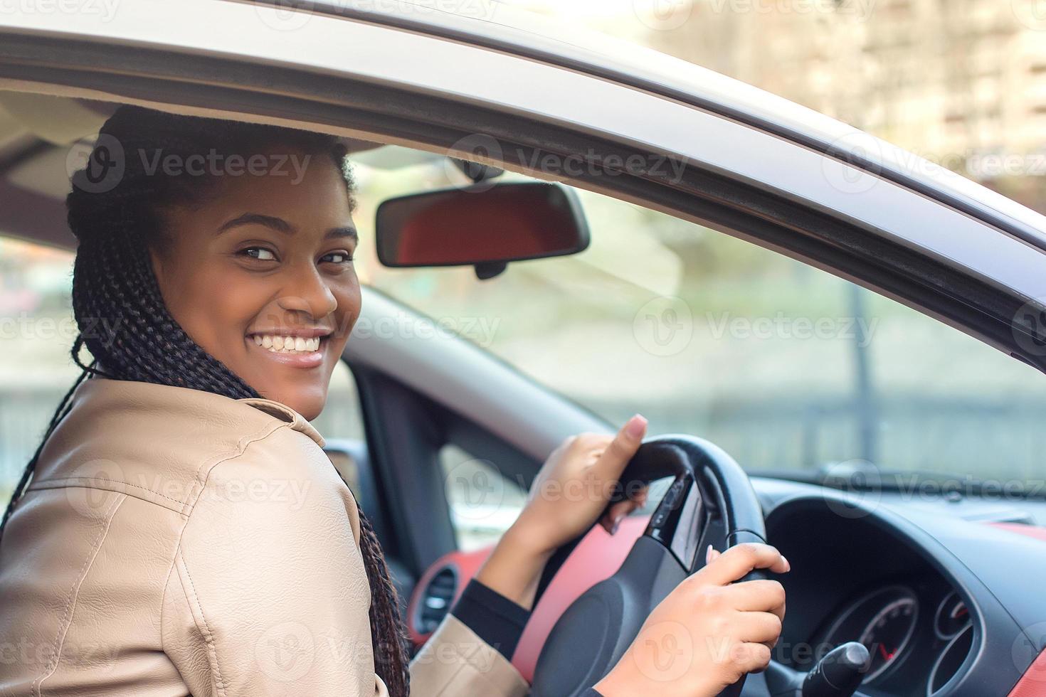 gelukkige Afro-Amerikaanse vrouw in een auto rijden, herfst-winter foto