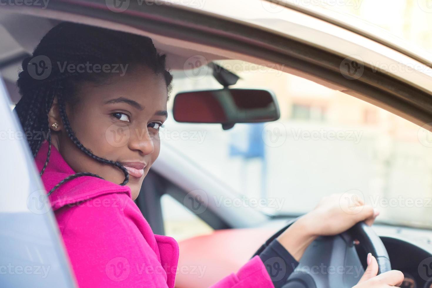 gelukkige Afro-Amerikaanse vrouw in een auto rijden, herfst-winter foto