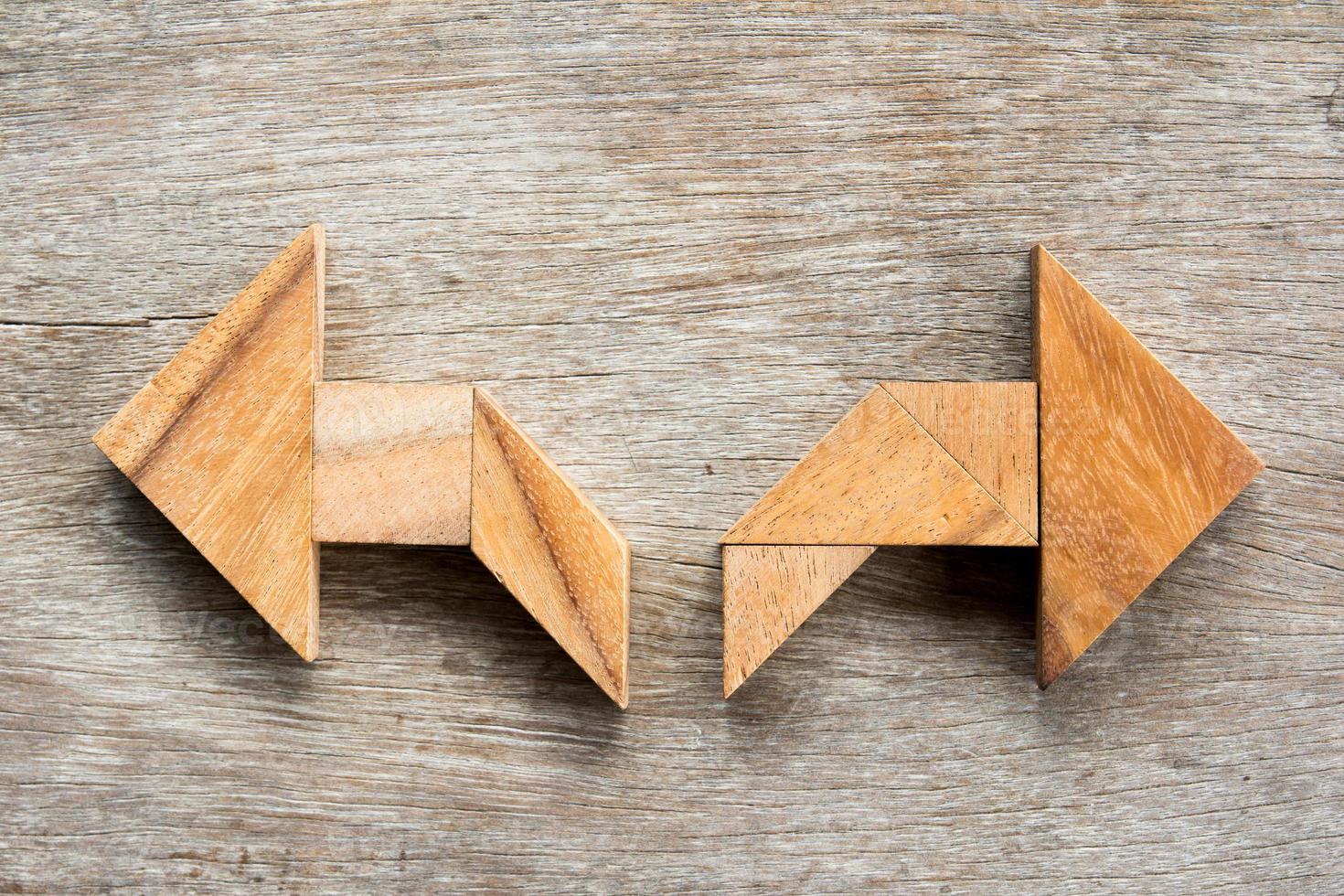tangram puzzel als twee richtingen pijlvorm op houten achtergrond foto