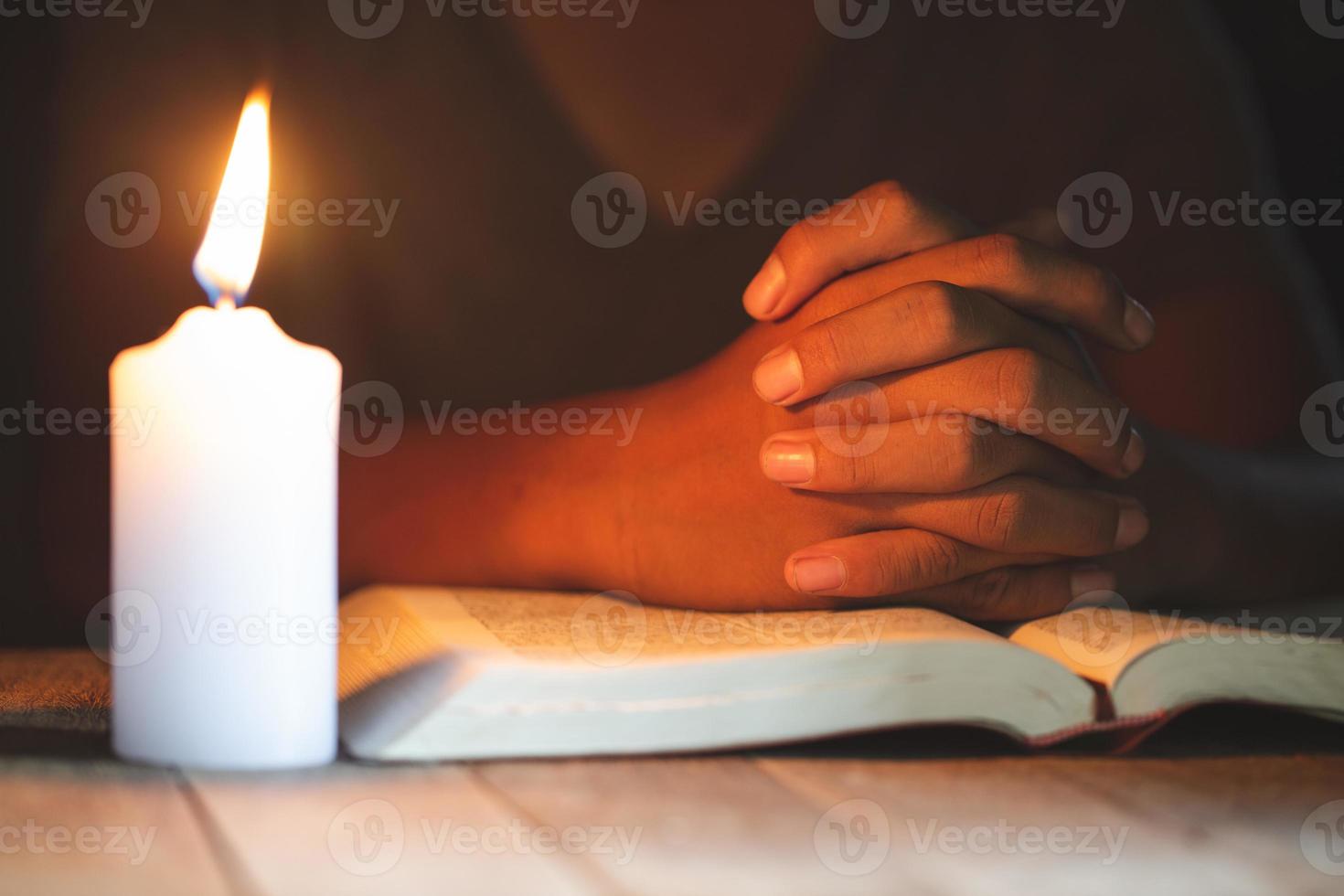 religieuze concepten, de jonge man bad op de bijbel in de kamer en stak de kaarsen aan om te verlichten. foto