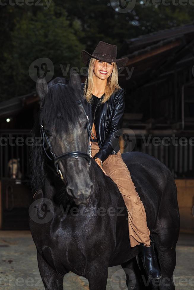 mooi jong meisje rijdt op haar bruine paard tijdens het rijden foto