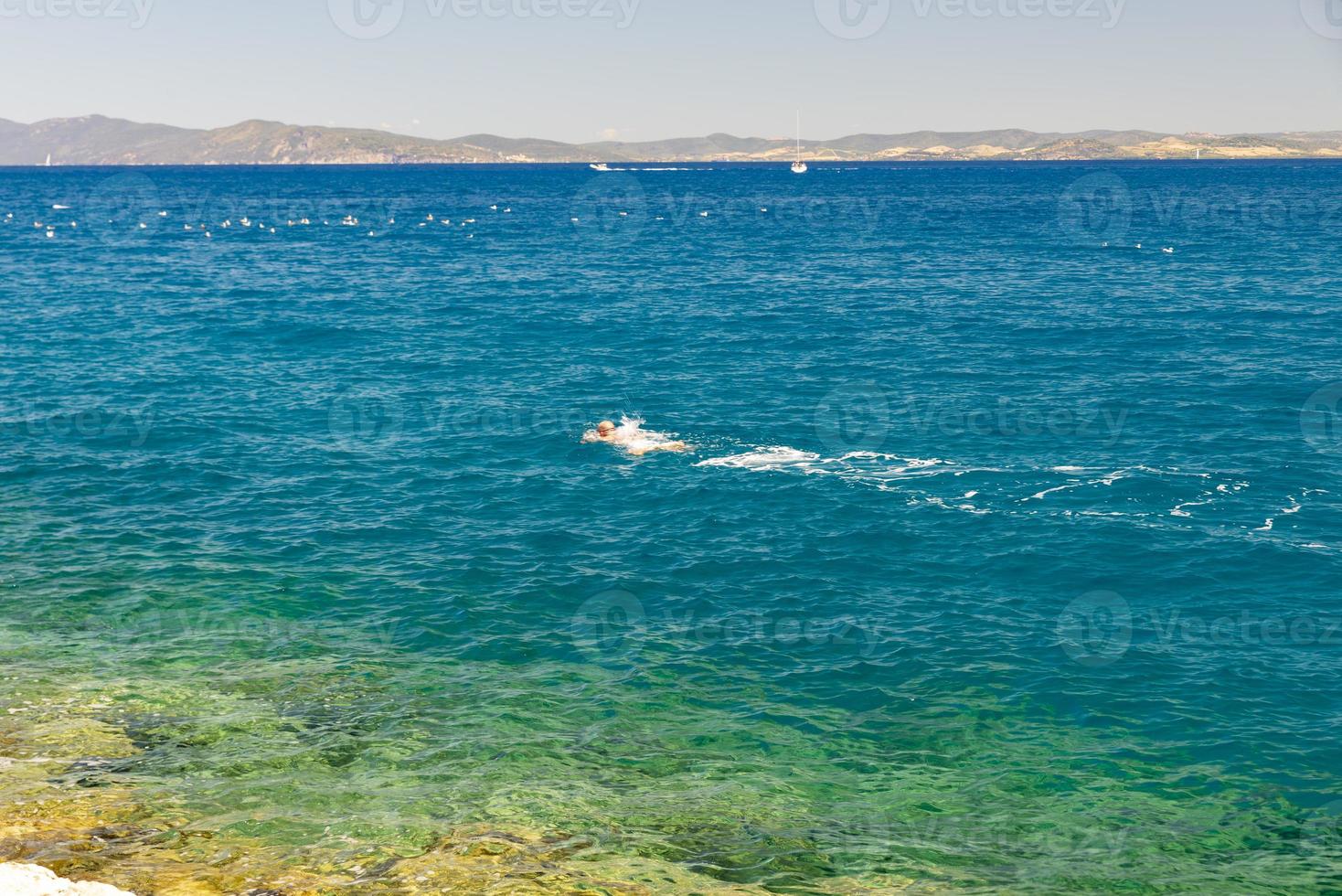 man zwemmen in de zee bij porto santo stefano, italië foto