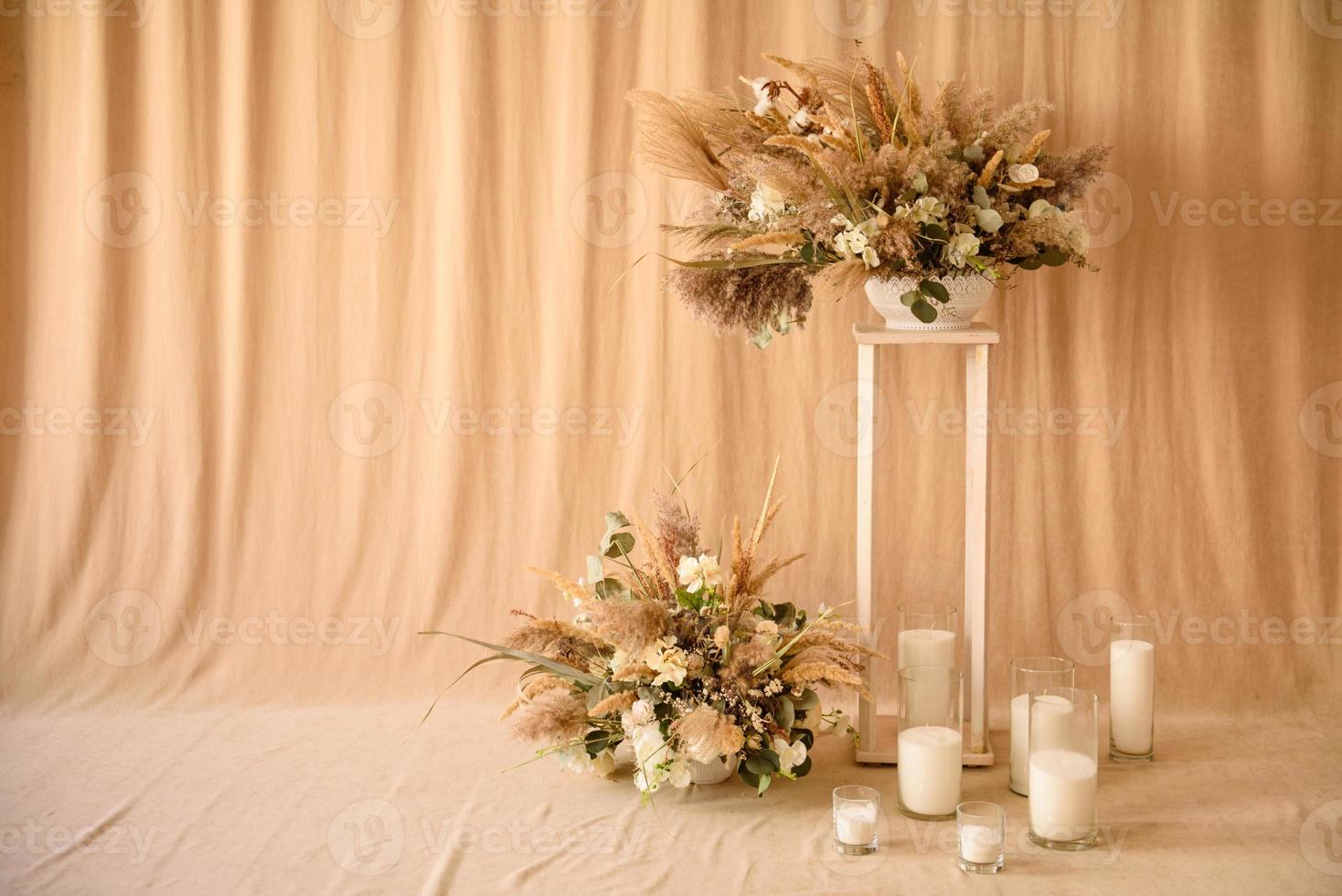 decoraties van droge mooie bloemen in een witte vaas op een beige stoffen achtergrond foto