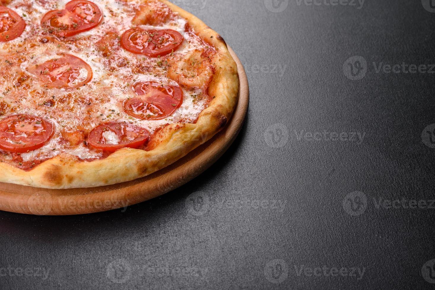 smakelijke verse ovenpizza met tomaten, kaas en basilicum op een betonnen ondergrond foto