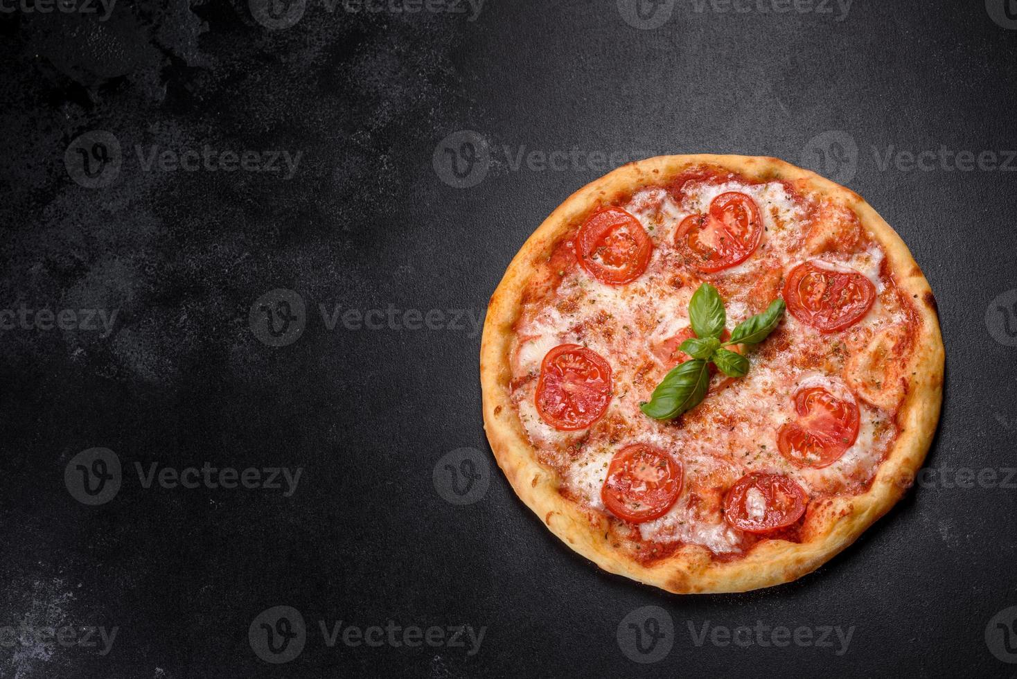 smakelijke verse ovenpizza met tomaten, kaas en basilicum op een betonnen ondergrond foto