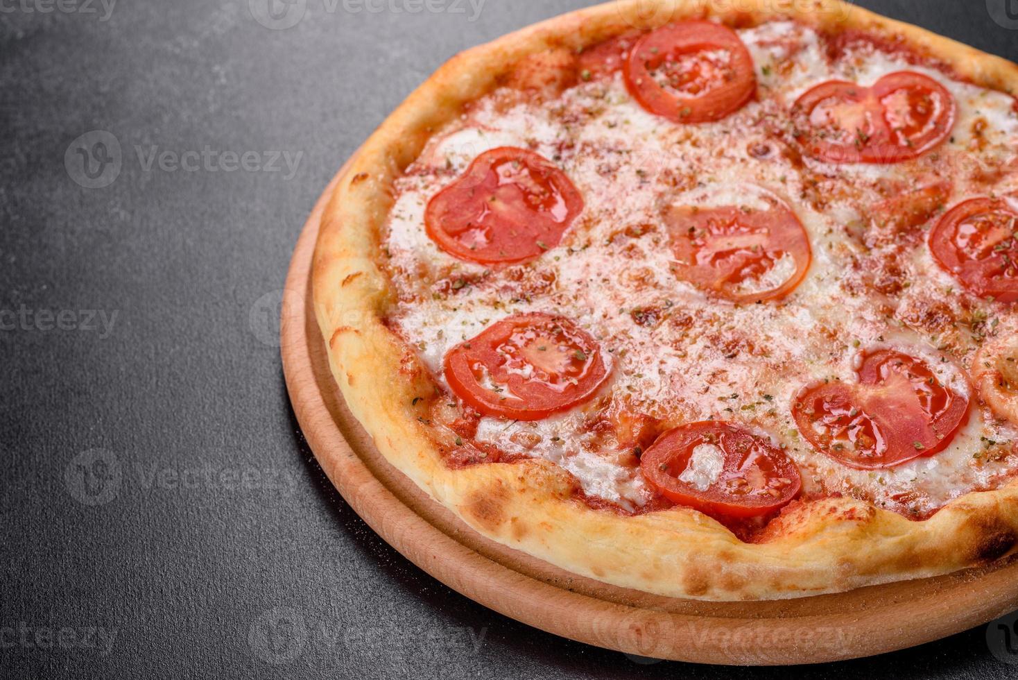 smakelijke verse ovenpizza met tomaten, kaas en basilicum op een betonnen ondergrond foto