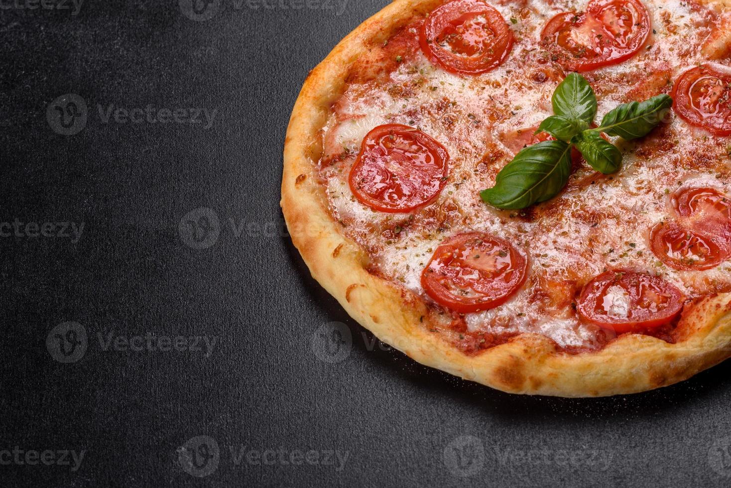 smakelijke verse ovenpizza met tomaten, kaas en basilicum op een betonnen ondergrond foto
