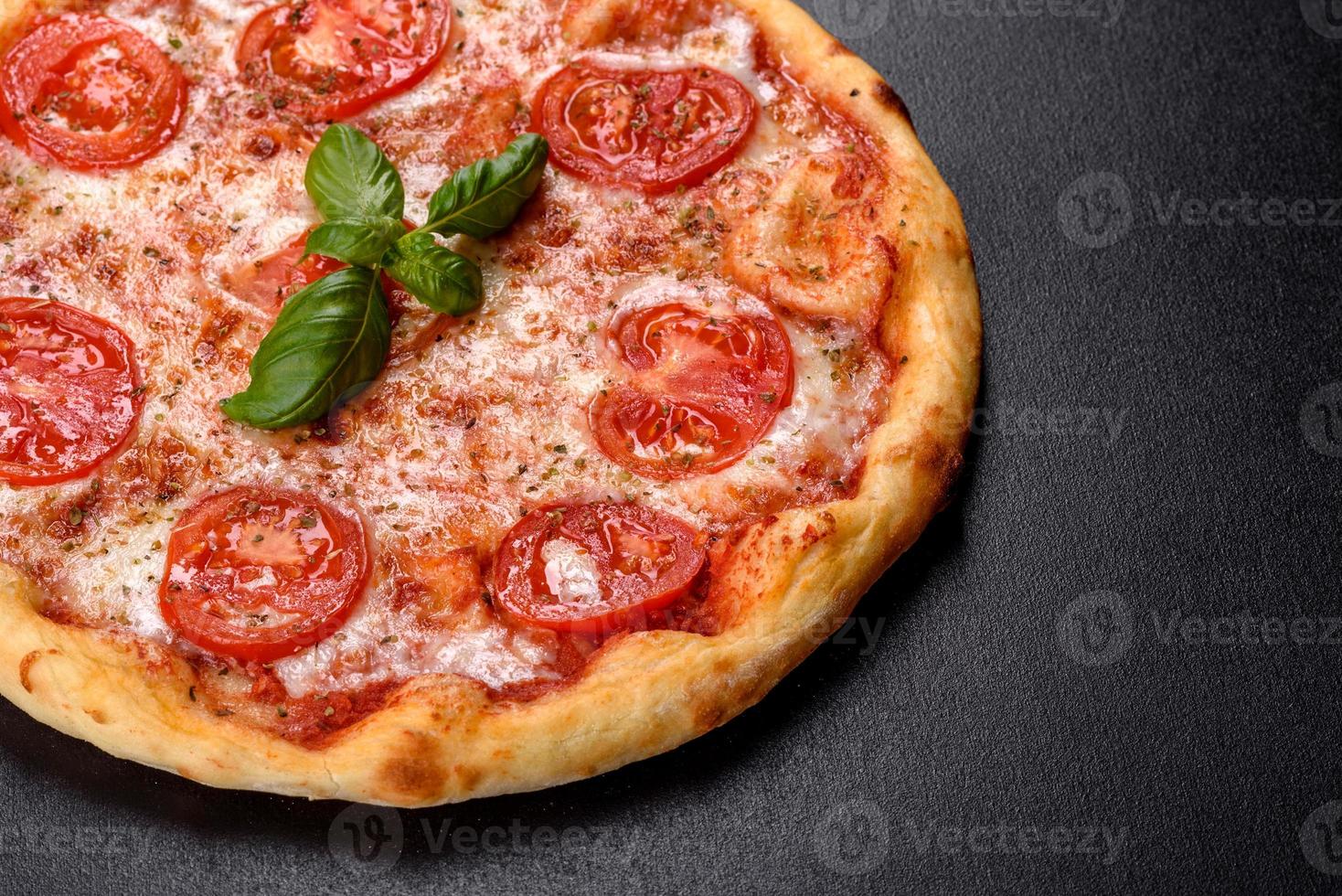 smakelijke verse ovenpizza met tomaten, kaas en basilicum op een betonnen ondergrond foto