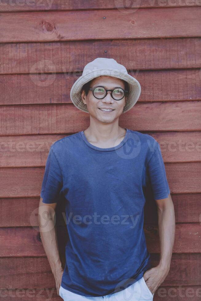 Aziatisch volwassen Mens toothy glimlachen met geluk gezicht staand tegen houten muur foto
