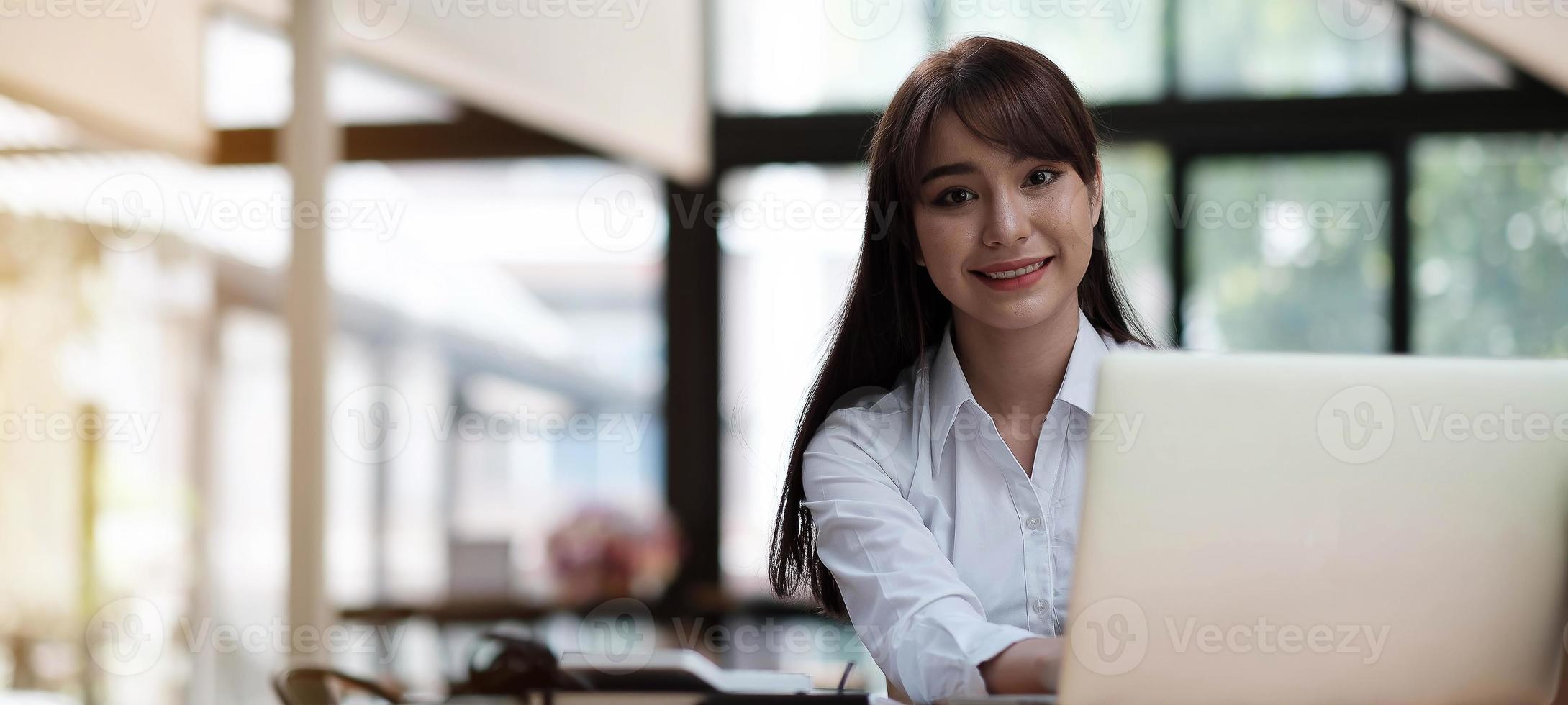 portret van een mooie jonge vrouw die studeert terwijl ze aan tafel zit foto