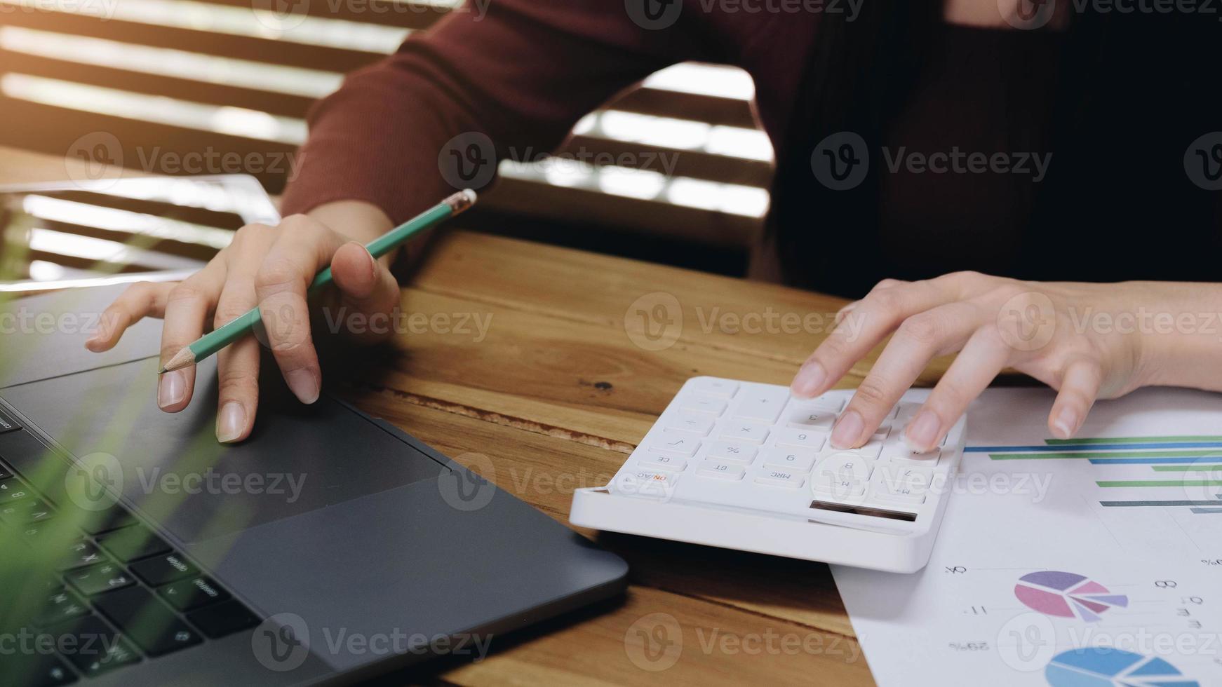 vrouw met behulp van rekenmachine en laptop foto