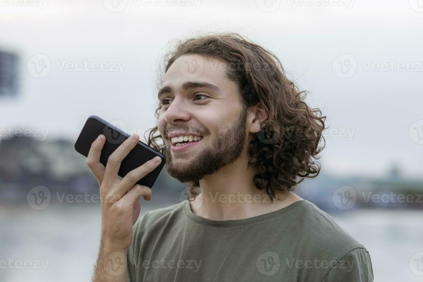 portret van gelukkig jong Mens gebruik makend van smartphone buitenshuis foto