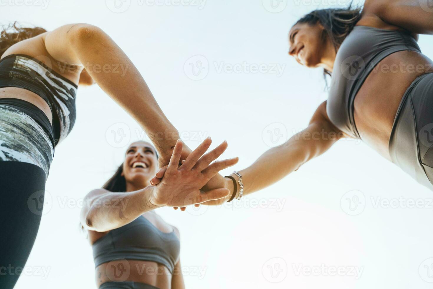 drie gelukkig sportief Dames stapelen hun handen na aan het doen sport- foto