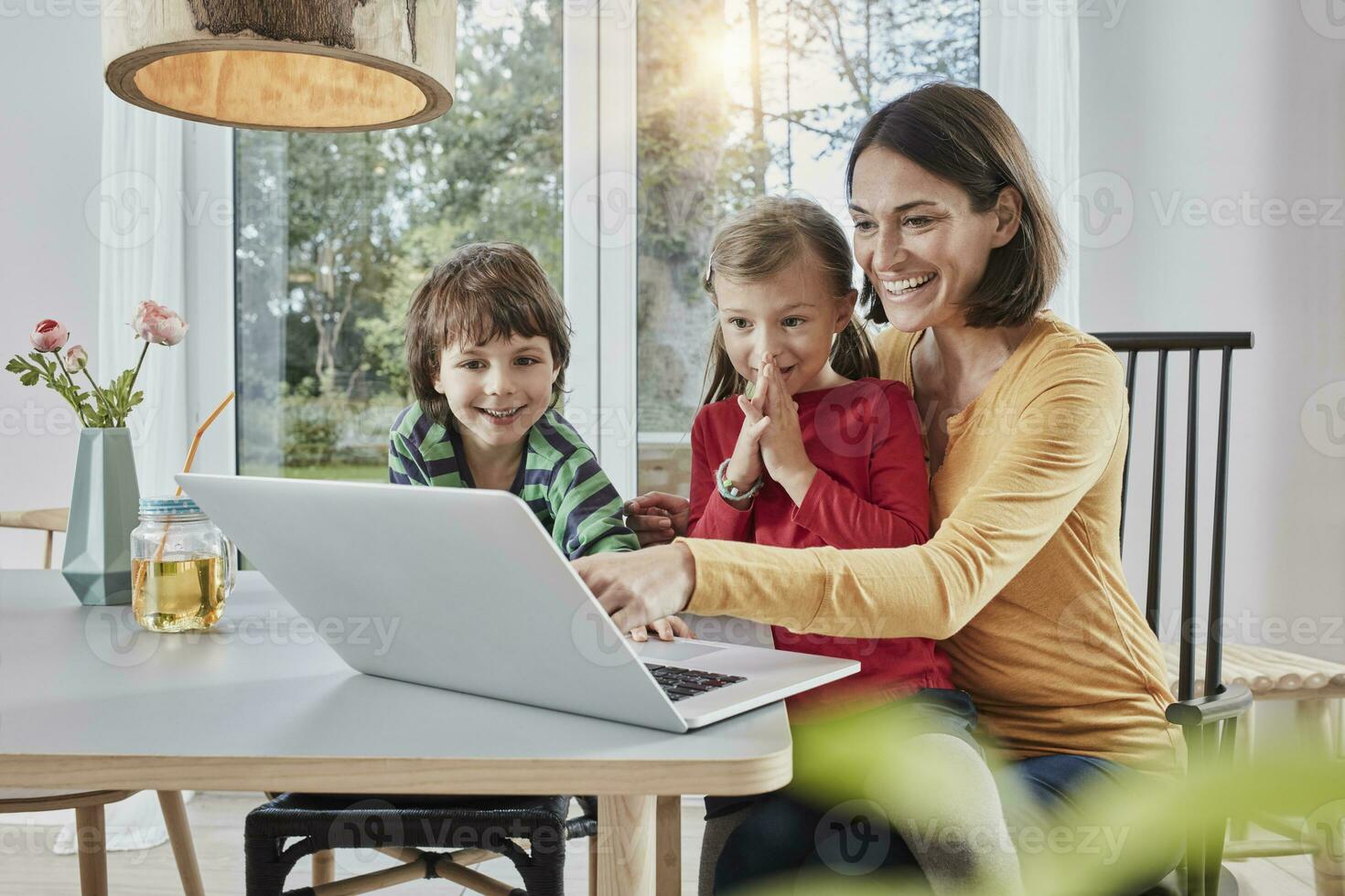 gelukkig moeder met twee kinderen gebruik makend van laptop Bij huis foto