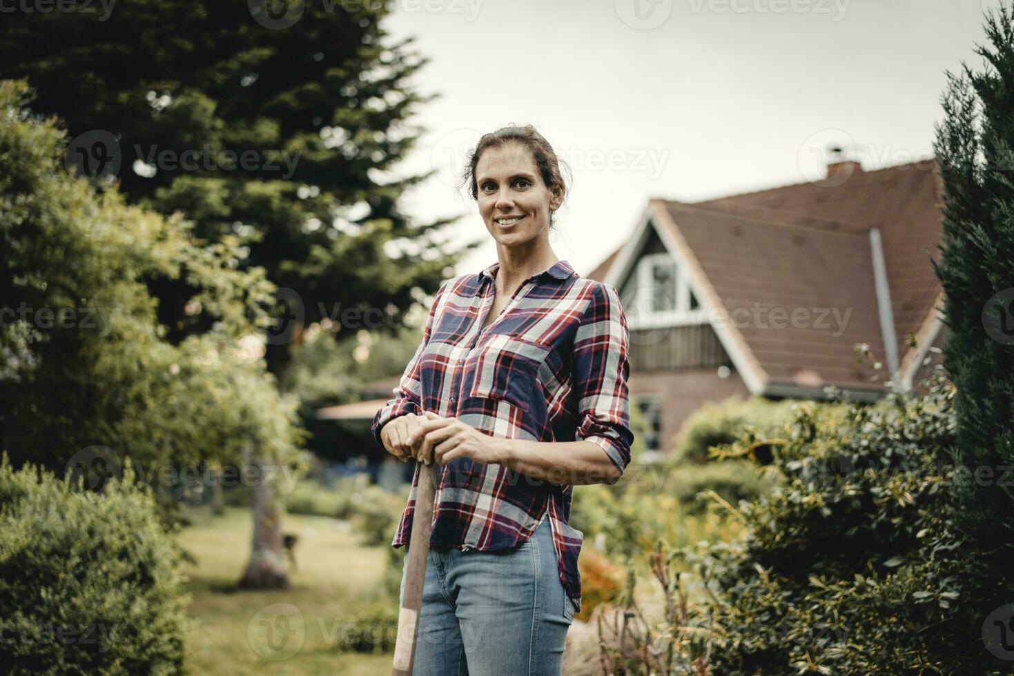 trots huis eigenaar staand in haar tuin met een spade foto