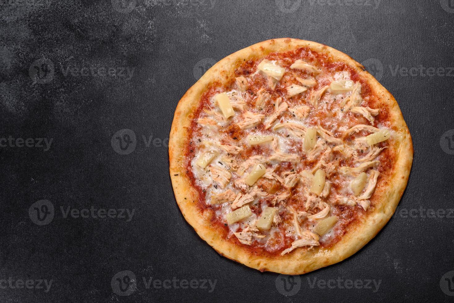 smakelijke verse ovenpizza met tomaten, kaas en ananas op een donkere betonnen ondergrond foto