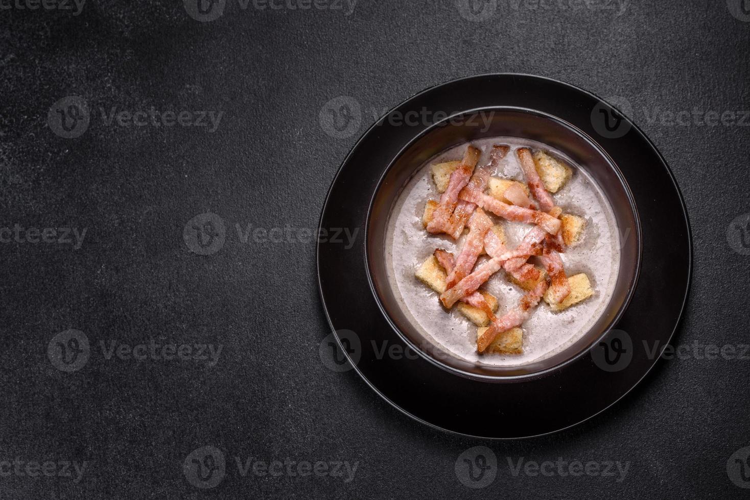 verse heerlijke warme pureesoep met champignons en spek in een zwart bord foto