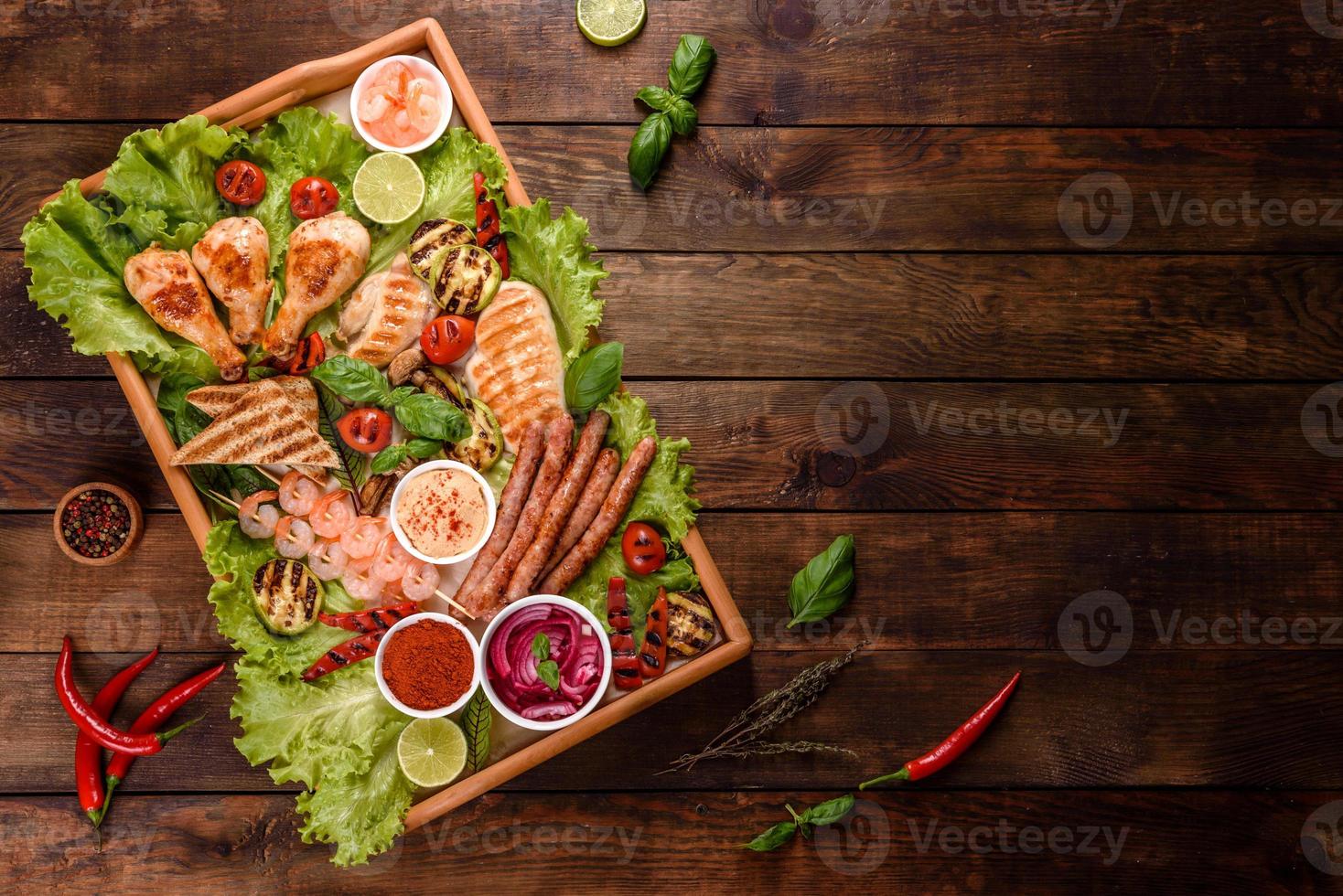 samenstelling van worst, kip, varkensvlees en garnalen bereid op de grill, evenals groenten bereid op de grill met specerijen en kruiden foto