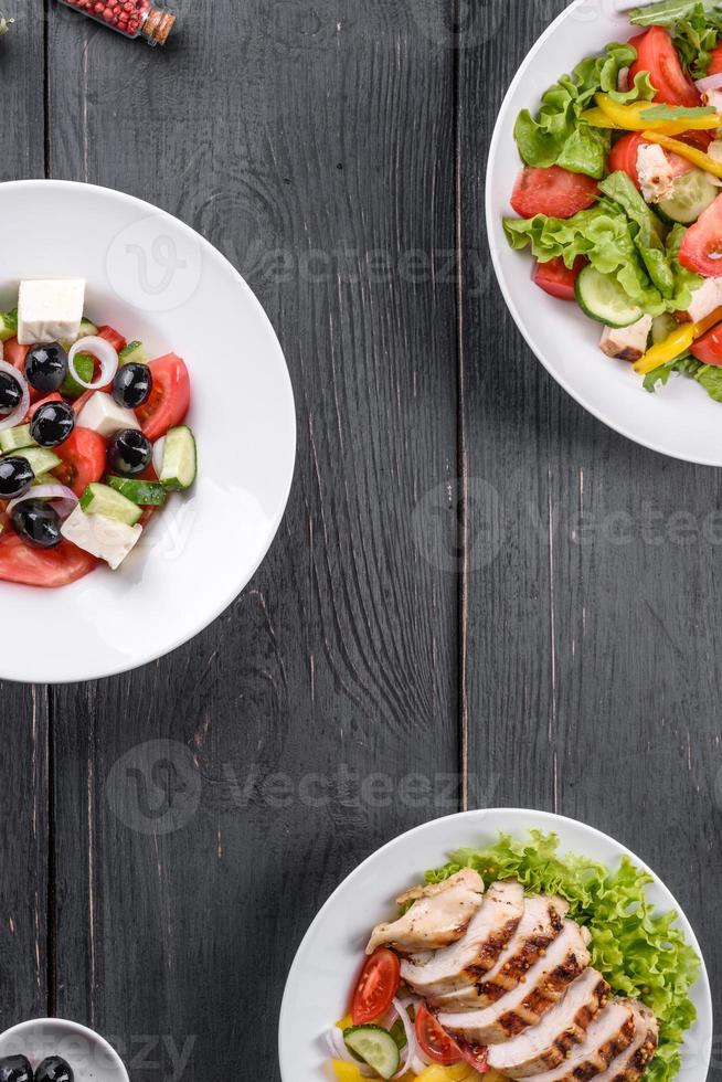 drie verse heerlijke salades met kip, tomaat, komkommer, uien en greens met olijfolie foto