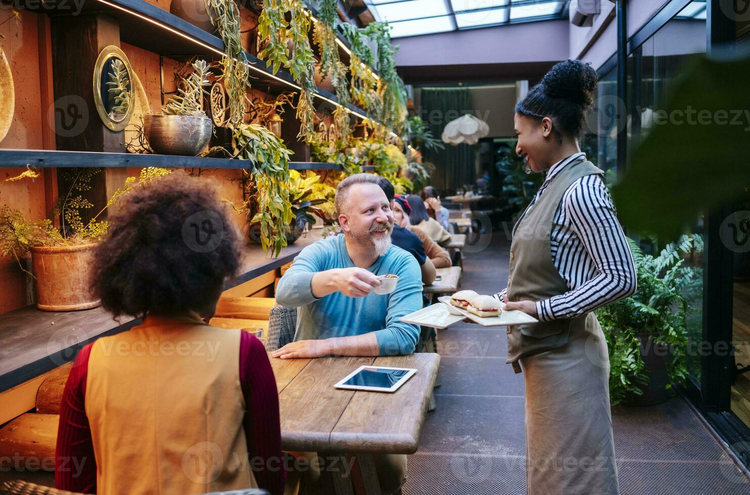 mensen zittend in restaurant, terwijl serveerster is portie voedsel foto