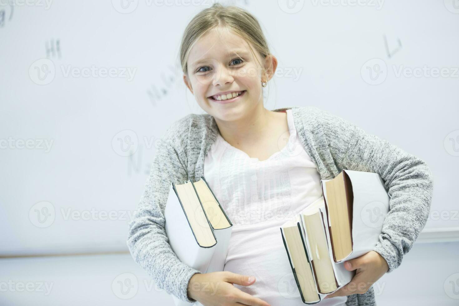 portret van gelukkig schoolmeisje draag- boeken in klasse foto