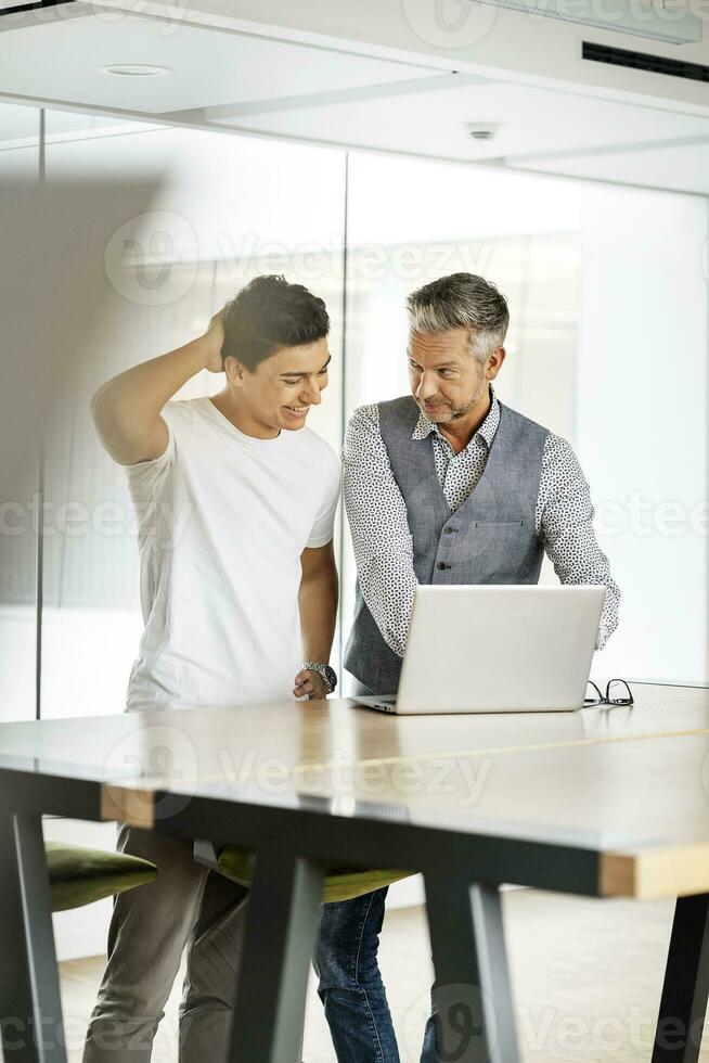 senior zakenman werken met jong collega, gebruik makend van laptop foto