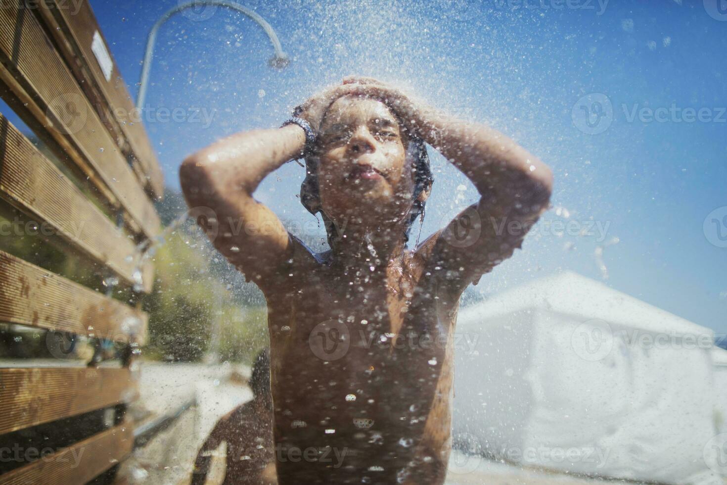 weinig jongen nemen douche Aan de strand foto