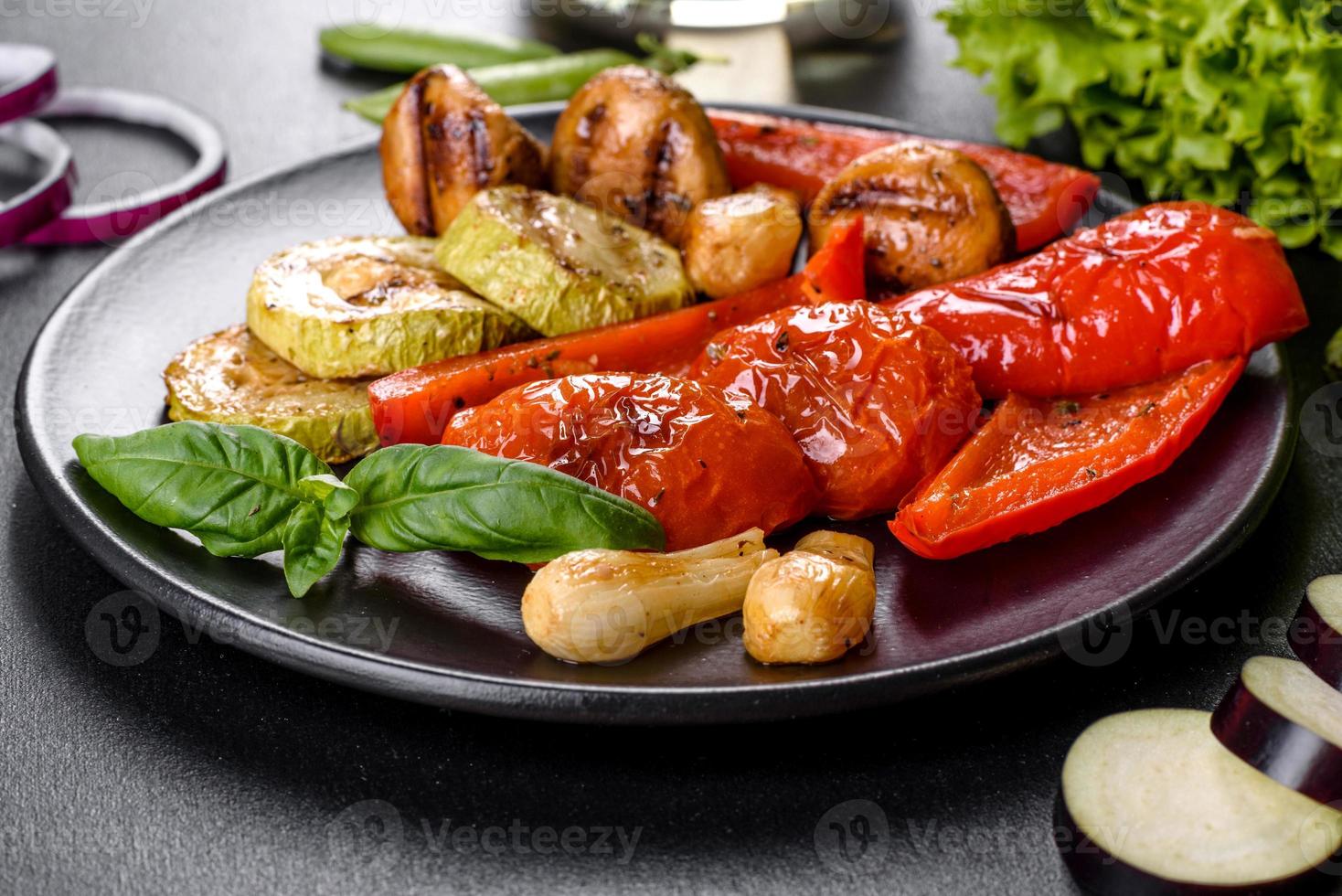 smakelijke verse groentengrill. tomaten, paprika's, champignons, courgette en uien op een zwart bord foto