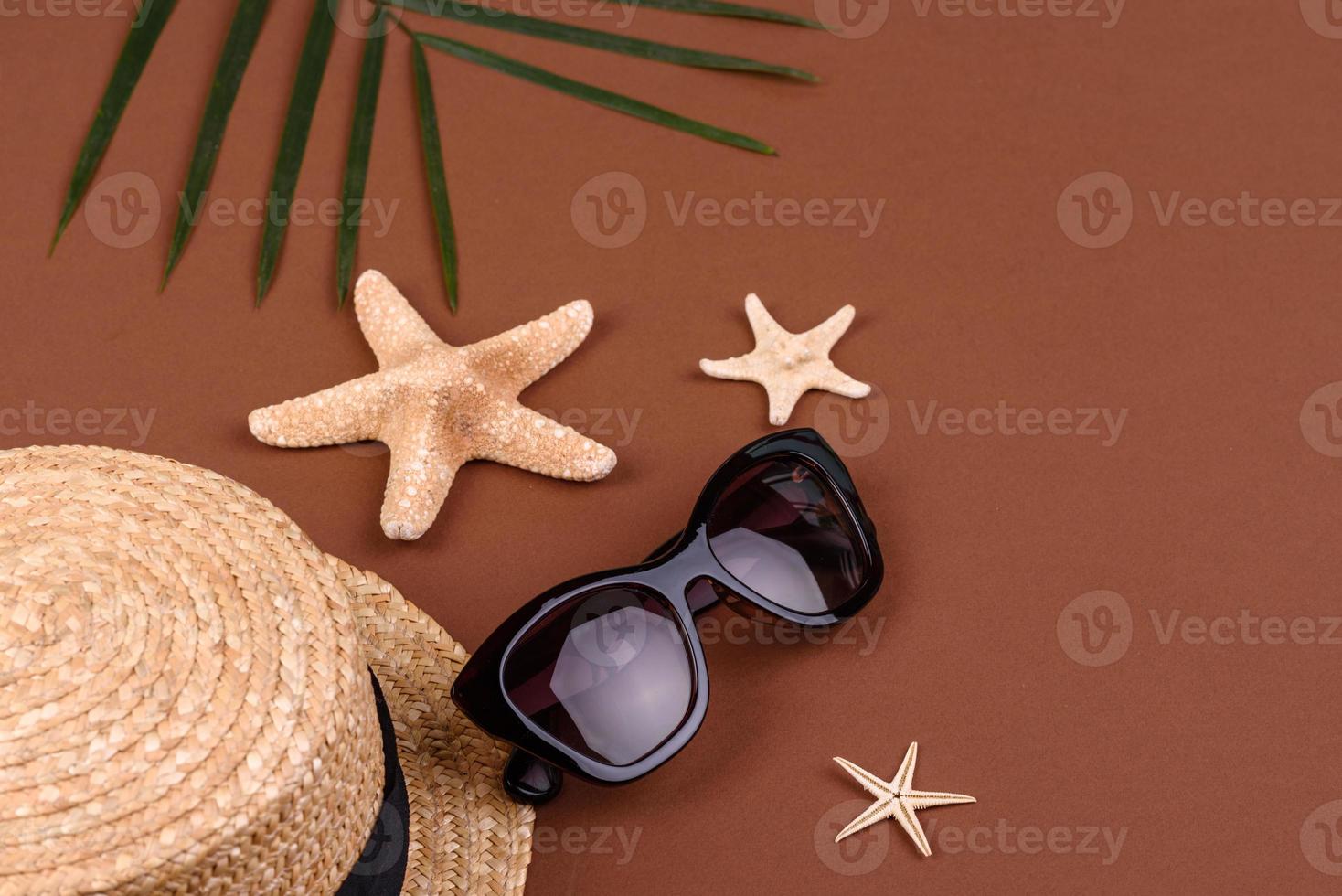 strandaccessoires, bril en hoed met schelpen en zeesterren op een gekleurde achtergrond. zomer achtergrond foto