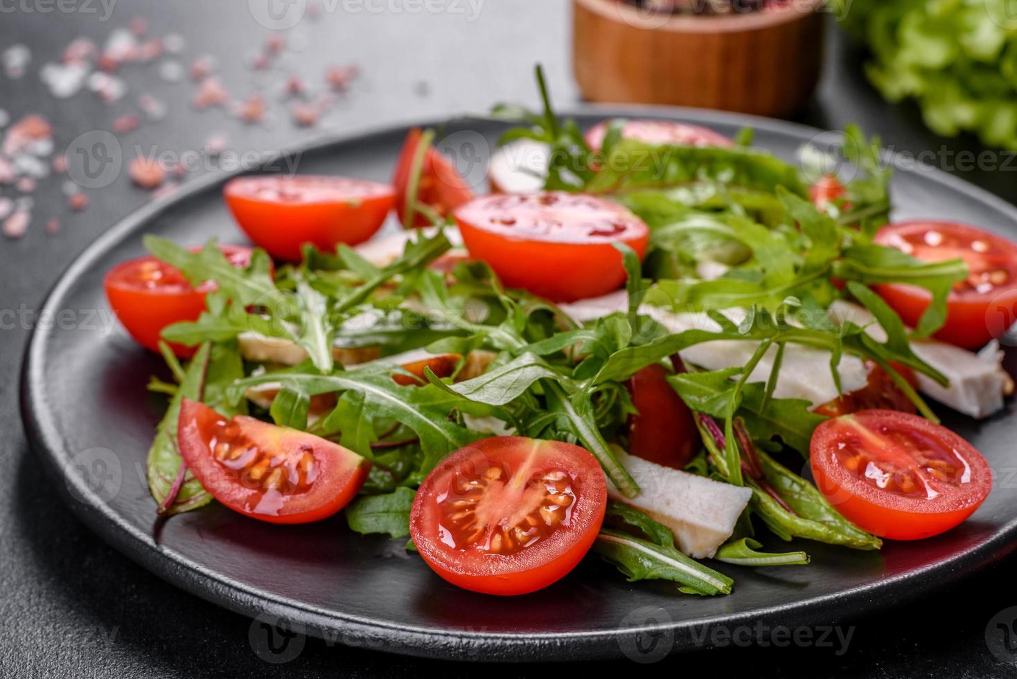 stukjes kip, tomaten en slablaadjes op een donkere betonnen ondergrond foto