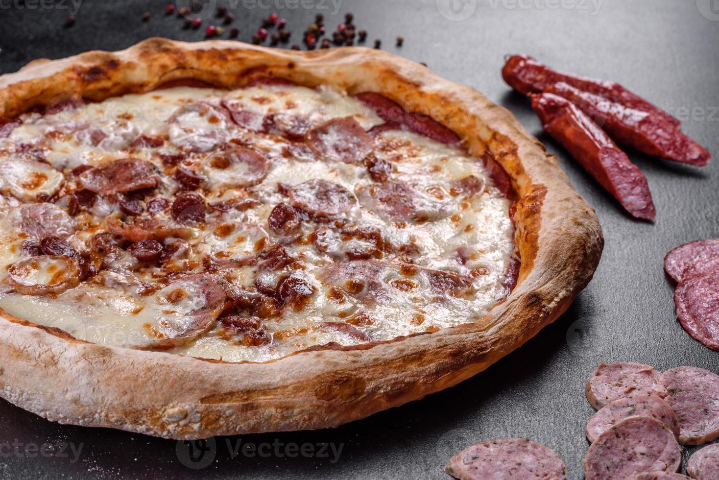 verse heerlijke Italiaanse pizza met vier soorten vlees op een donkere betonnen ondergrond concrete foto