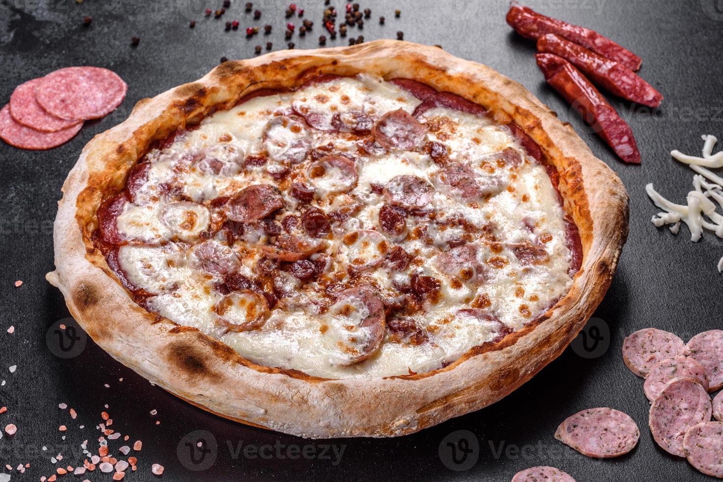 verse heerlijke Italiaanse pizza met vier soorten vlees op een donkere betonnen ondergrond concrete foto