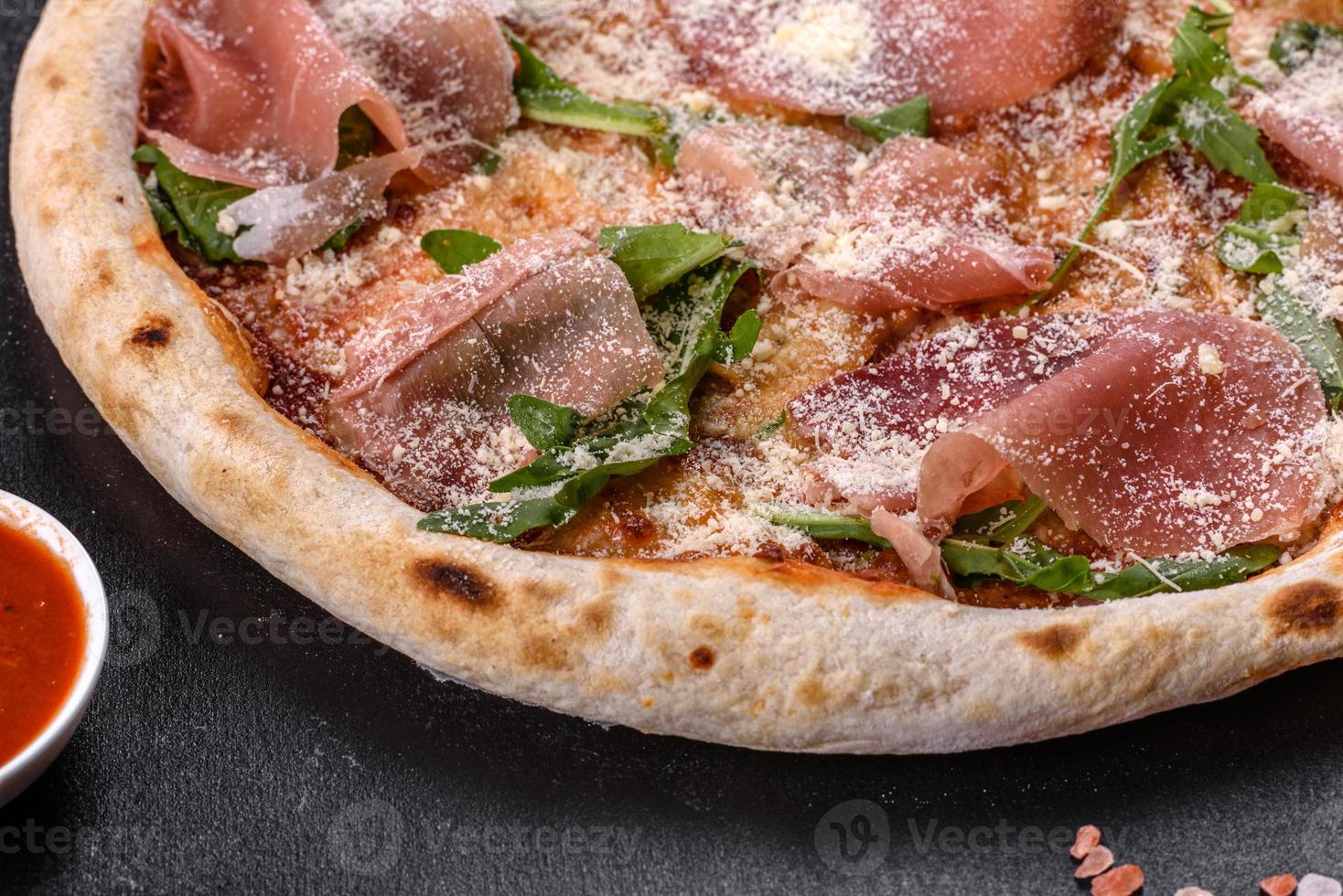 verse heerlijke Italiaanse pizza met een prosciutto op een donkere betonnen achtergrond concrete foto