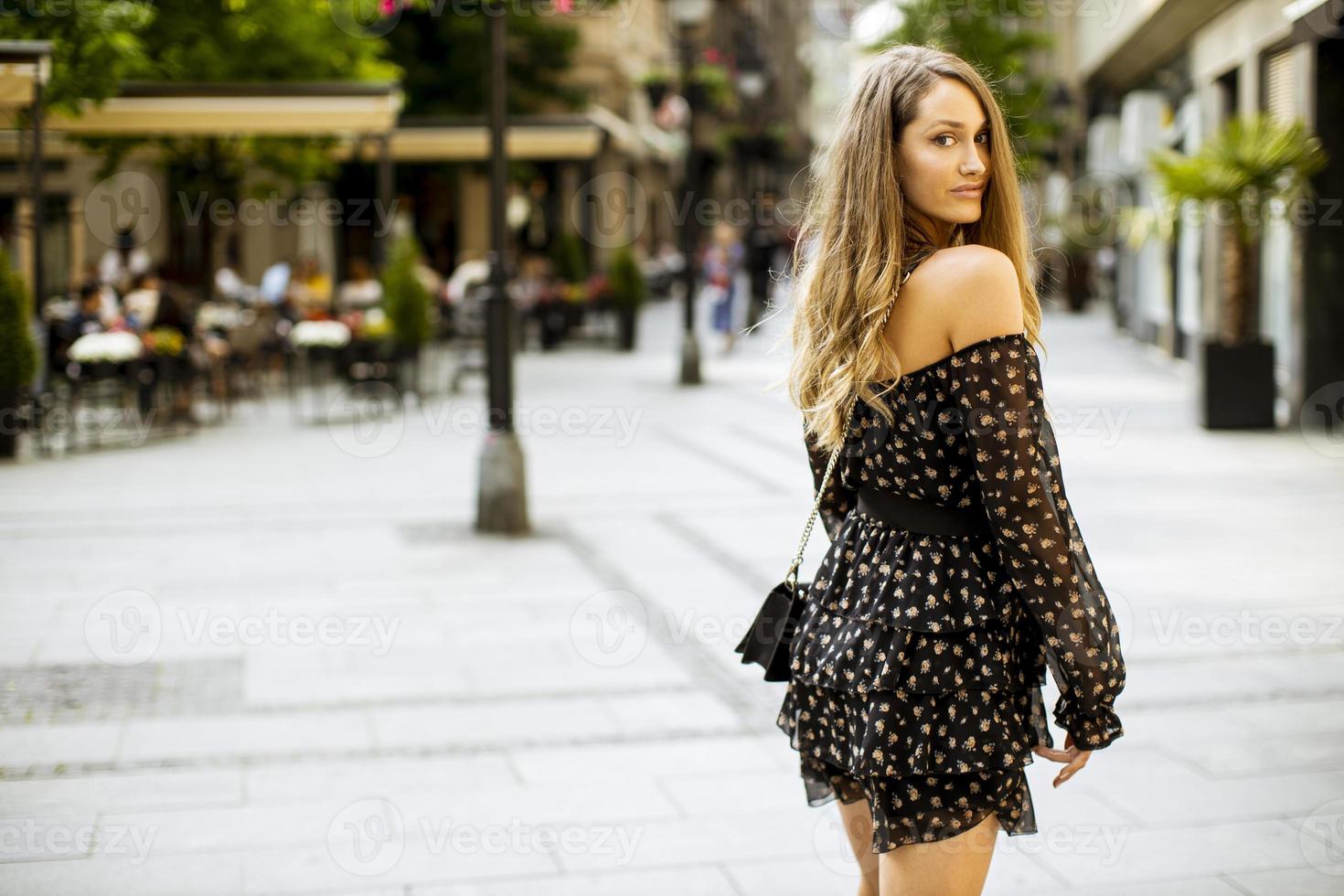 jonge langharige brunette vrouw die op straat loopt foto