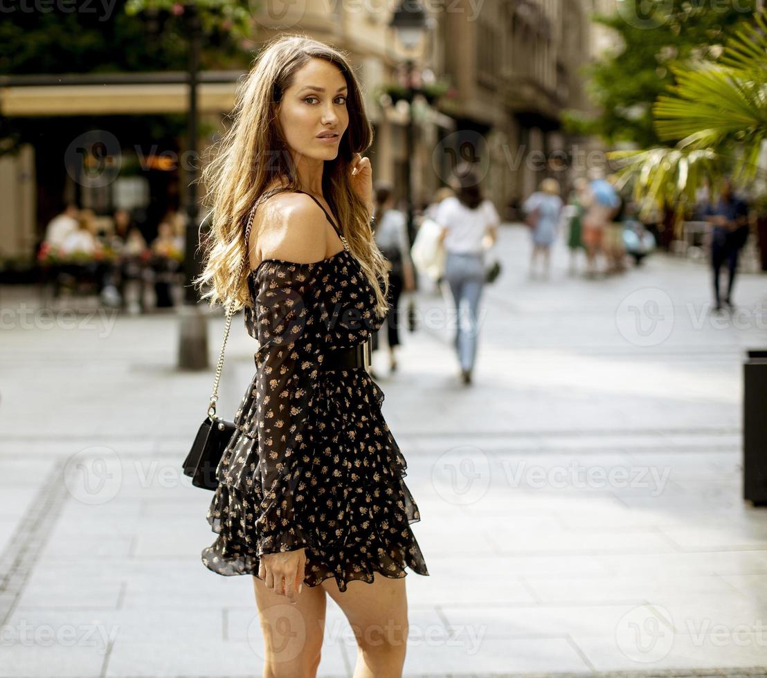 jonge langharige brunette vrouw die op straat loopt foto