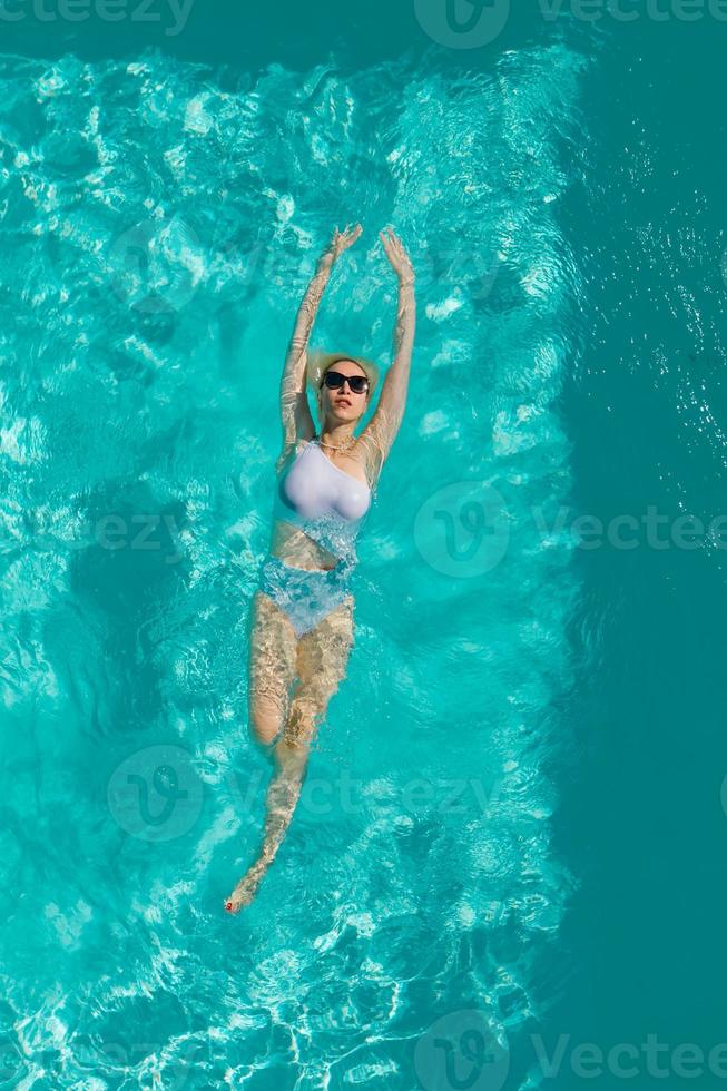 jonge mooie sexy meid die geniet van zwemmen in het privézwembad en ontspannen in de zon foto