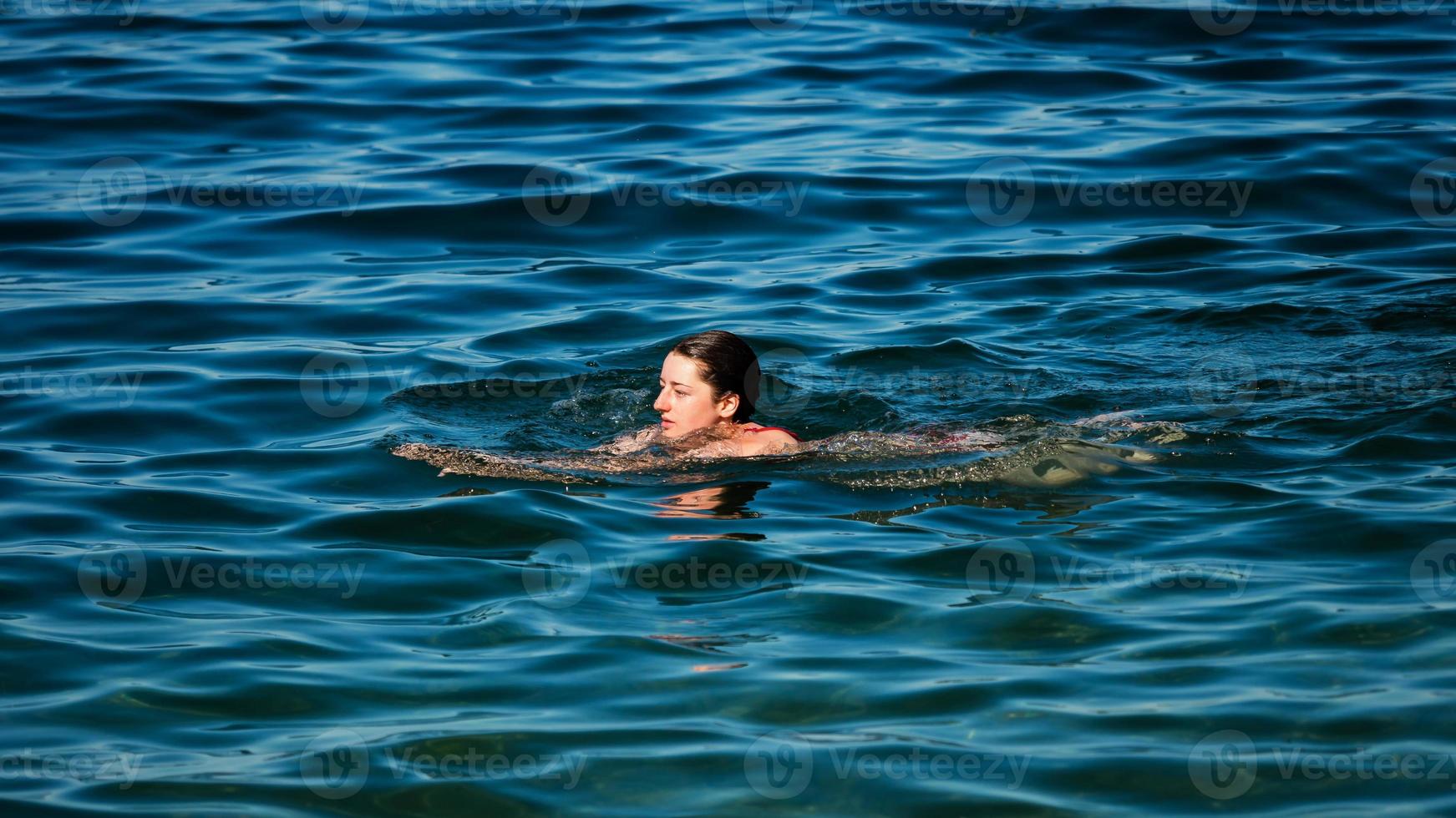 een jong meisje zwemt in het kristalheldere water van een bergmeer. foto