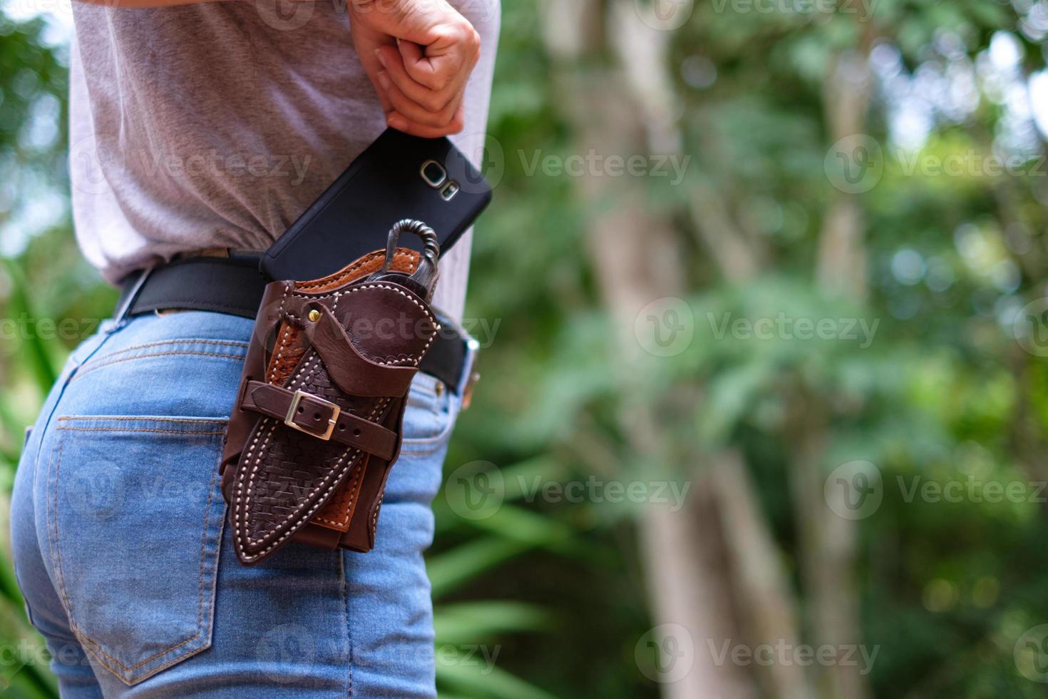 de vrouw trekt een smartphone uit de riem van een hoesje om haar middel foto