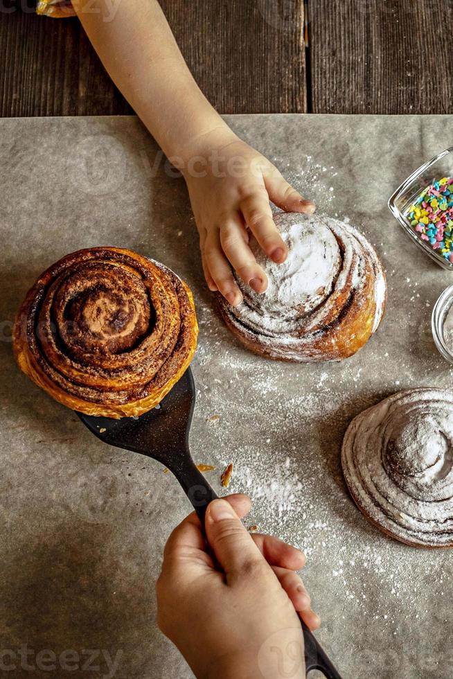 kinderhand pakt een versgebakken kaneelbroodje foto