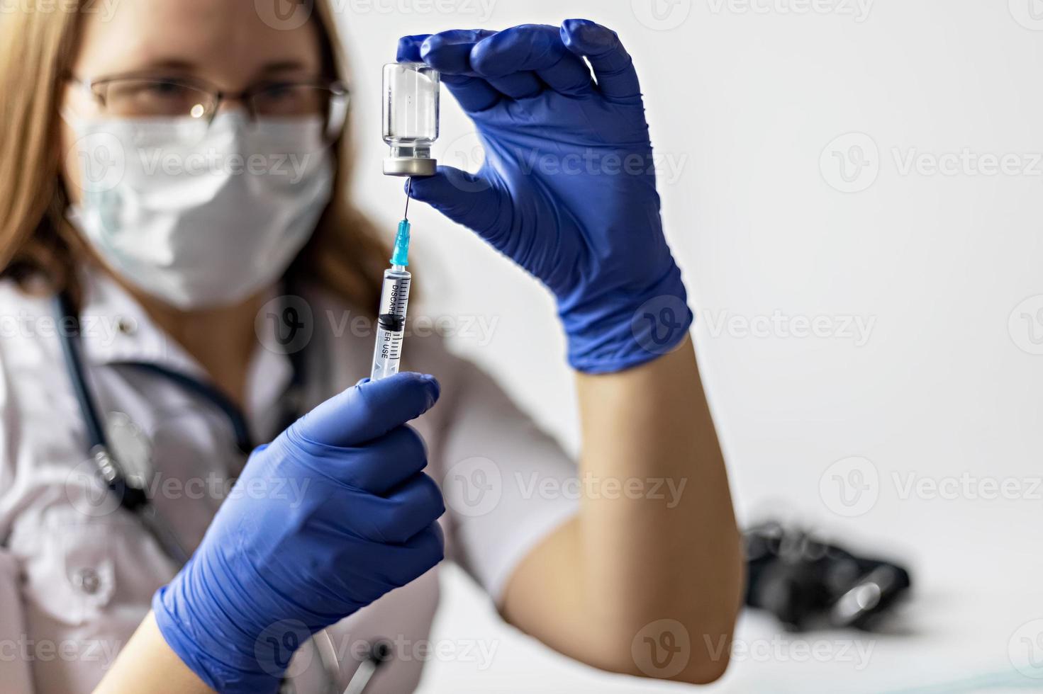 een vrouwelijke arts die een medisch masker draagt, trekt het coronavirusvaccin in een spuit in de kliniek. Het concept van vaccinatie, immunisatie, preventie tegen covid-19. foto