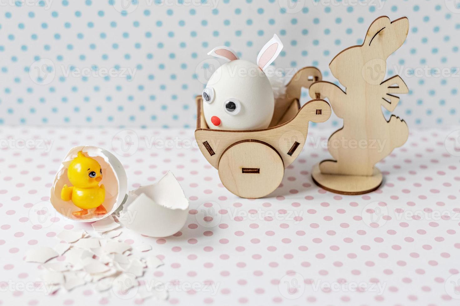 houten konijn met een kar met een ei met konijnenoren en een muilkorf. eierschaal met een uitgebroed kuiken. foto