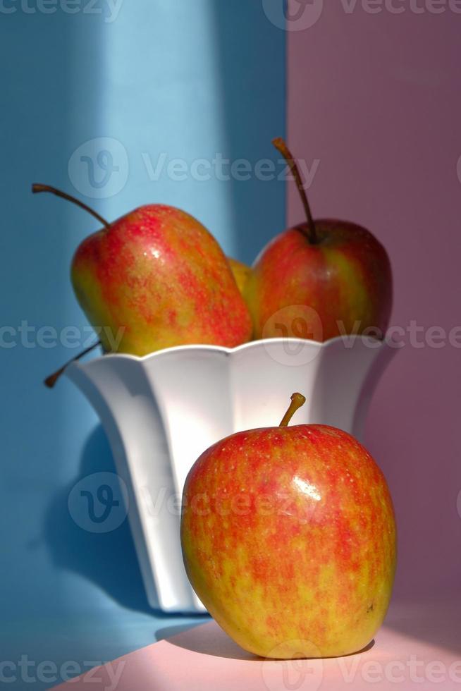 foto van een appel in een bak op een roze en blauwe achtergrond