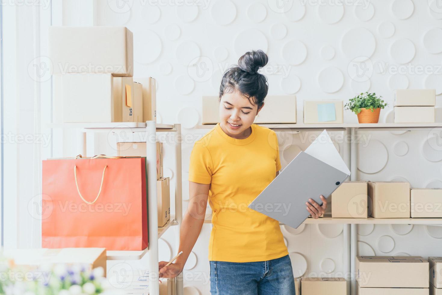 jonge aziatische vrouw die goederen controleert op voorraadplank in magazijn - online verkopen of online winkelen concept shopping foto