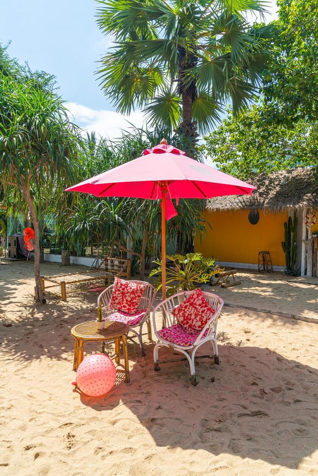 roze paraplu en stoel op tropisch strand foto