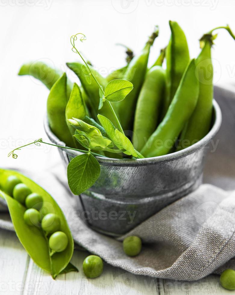 verse groene erwten in een kleine metalen emmer op oude houten achtergrond foto