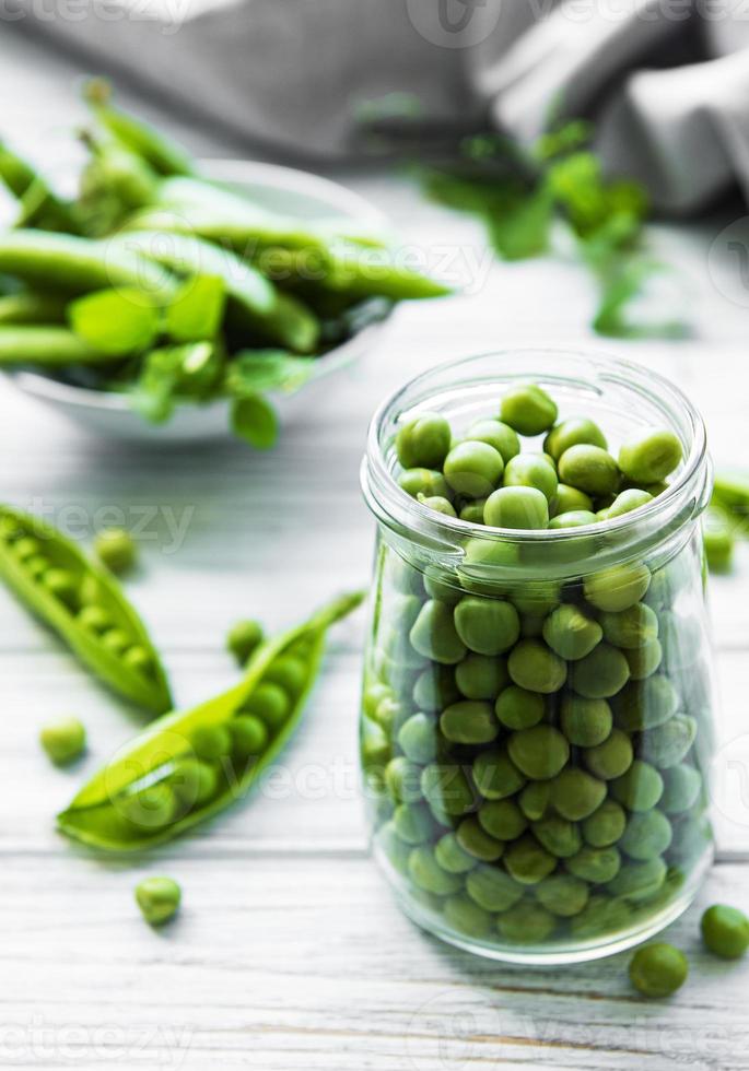 gezond eten. verse groene erwten in open glazen pot op houten achtergrond foto