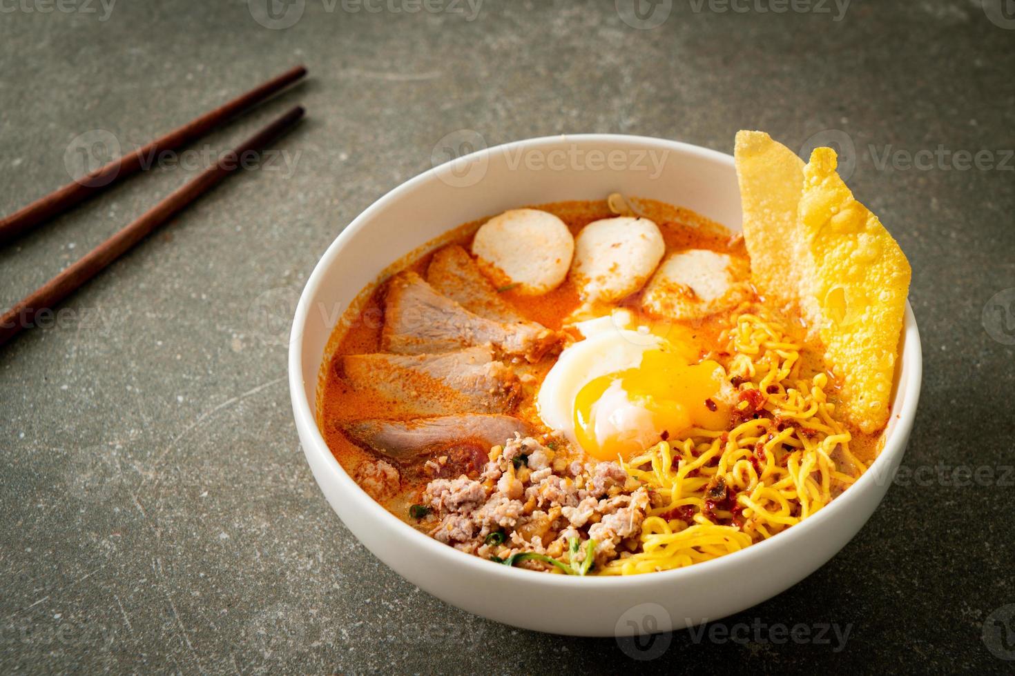 eiernoedels met varkensvlees en gehaktbal in pittige soep of tom yum noedels in aziatische stijl foto