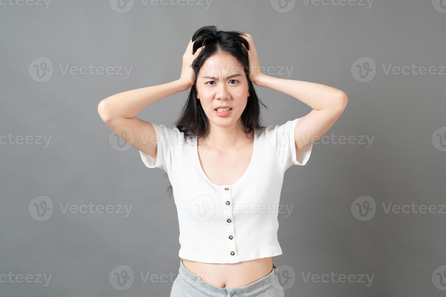 jonge aziatische vrouw met ernstig en gespannen gezicht in wit overhemd op grijze achtergrond foto